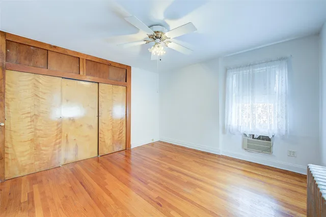 a view of an empty room with wooden floor and a chandelier fan