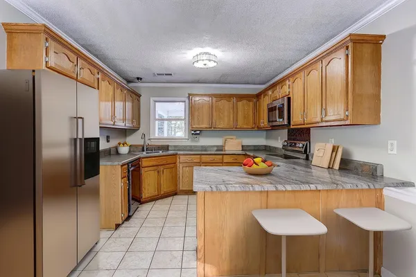 a kitchen with stainless steel appliances granite countertop a stove a sink a refrigerator white cabinets and a refrigerator