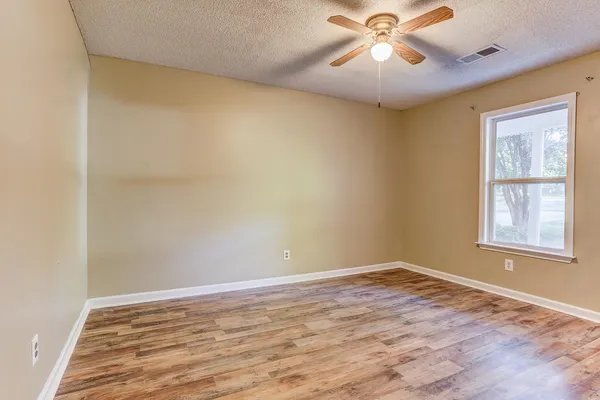 a view of an empty room with window and wooden floor