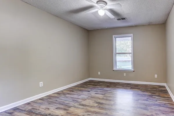 an empty room with wooden floor and windows
