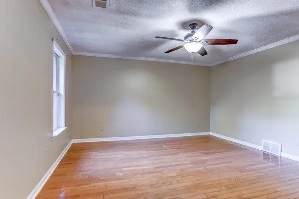 a view of a room with wooden floor ceiling fan and window
