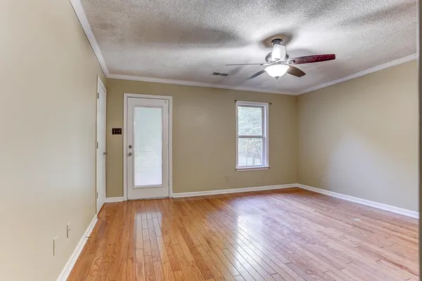 a view of an empty room with wooden floor and a window