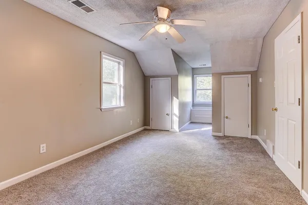 an empty room with chandelier fan and windows