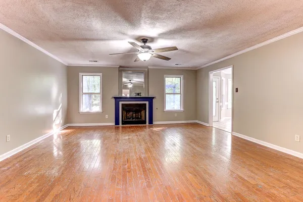 a view of an empty room with window and wooden floor