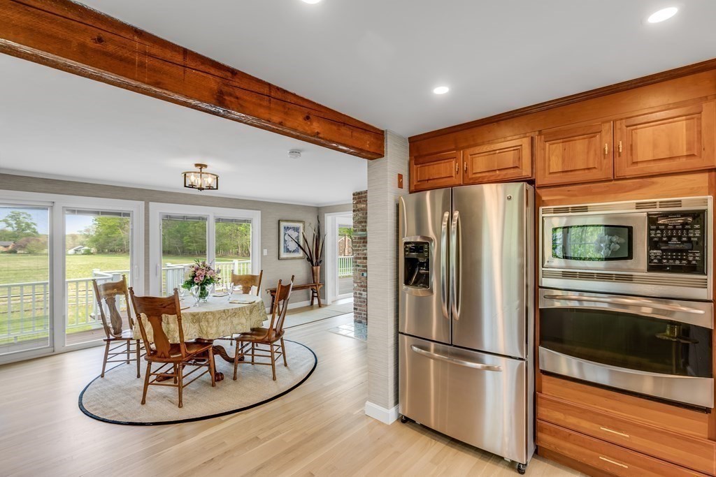 3 Longmeadow Way Hamilton, MA 01982 - Photo 11 of 41 a kitchen with stainless steel appliances granite countertop a refrigerator a stove a dining table and chairs with wooden floor