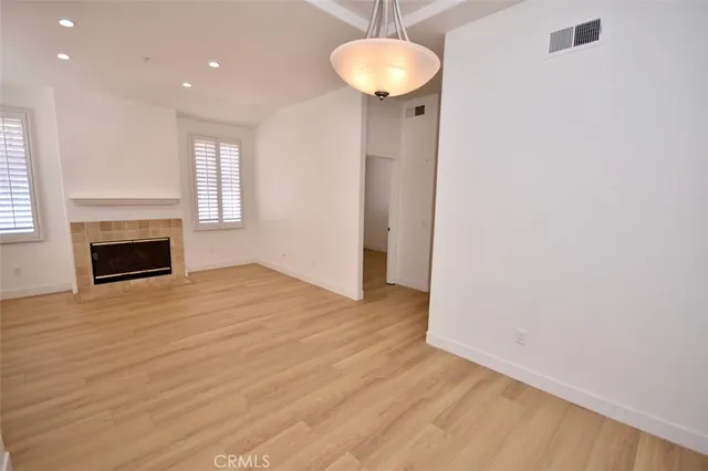an empty room with wooden floor a fireplace and a window