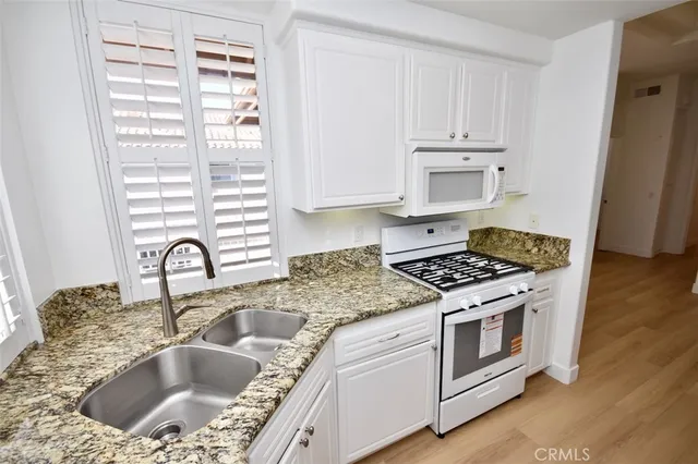 a kitchen with granite countertop a sink stainless steel appliances and cabinets