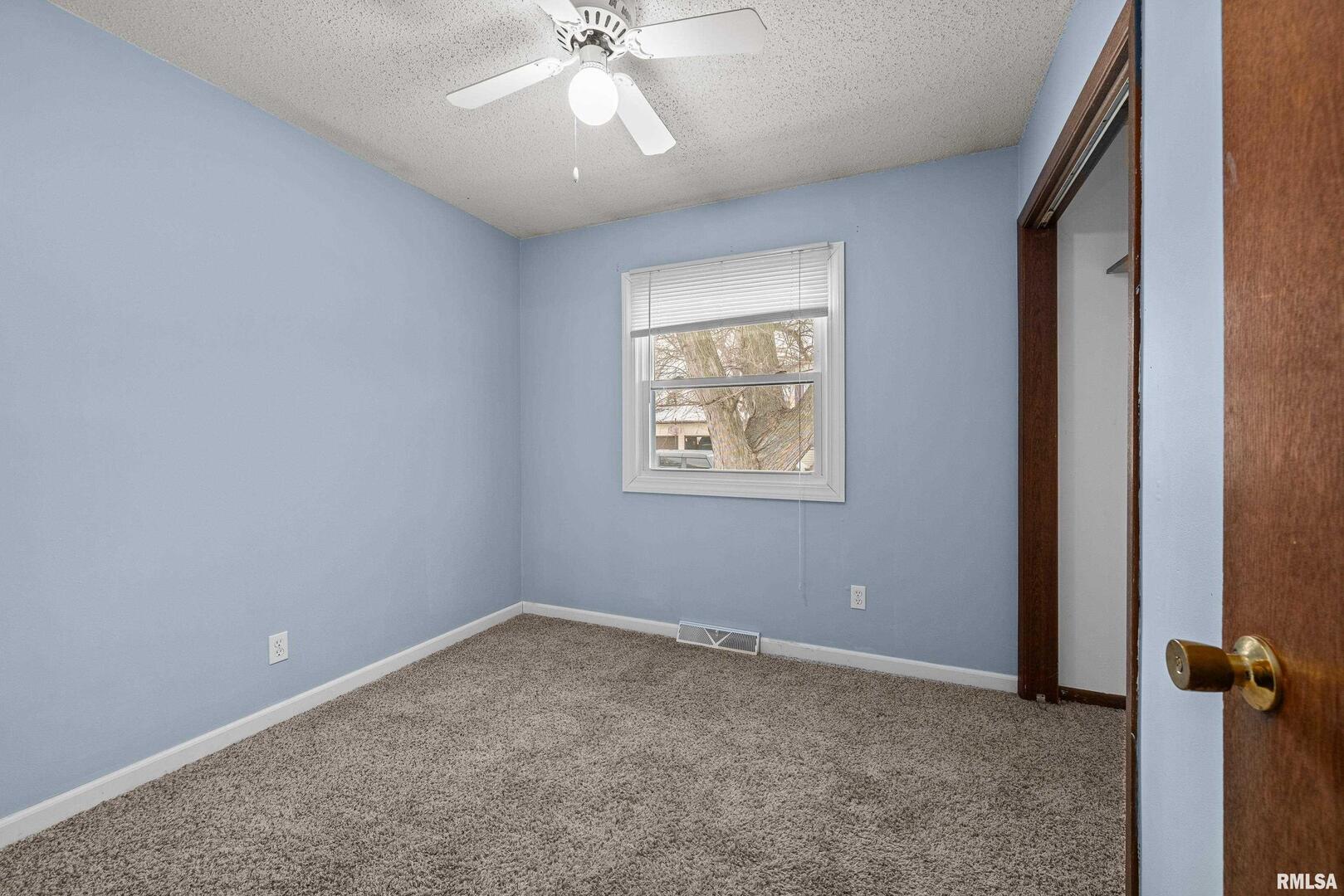 617 6th Street Camanche, IA 52730 - Photo 13 of 25 an empty room with a chandelier fan and windows