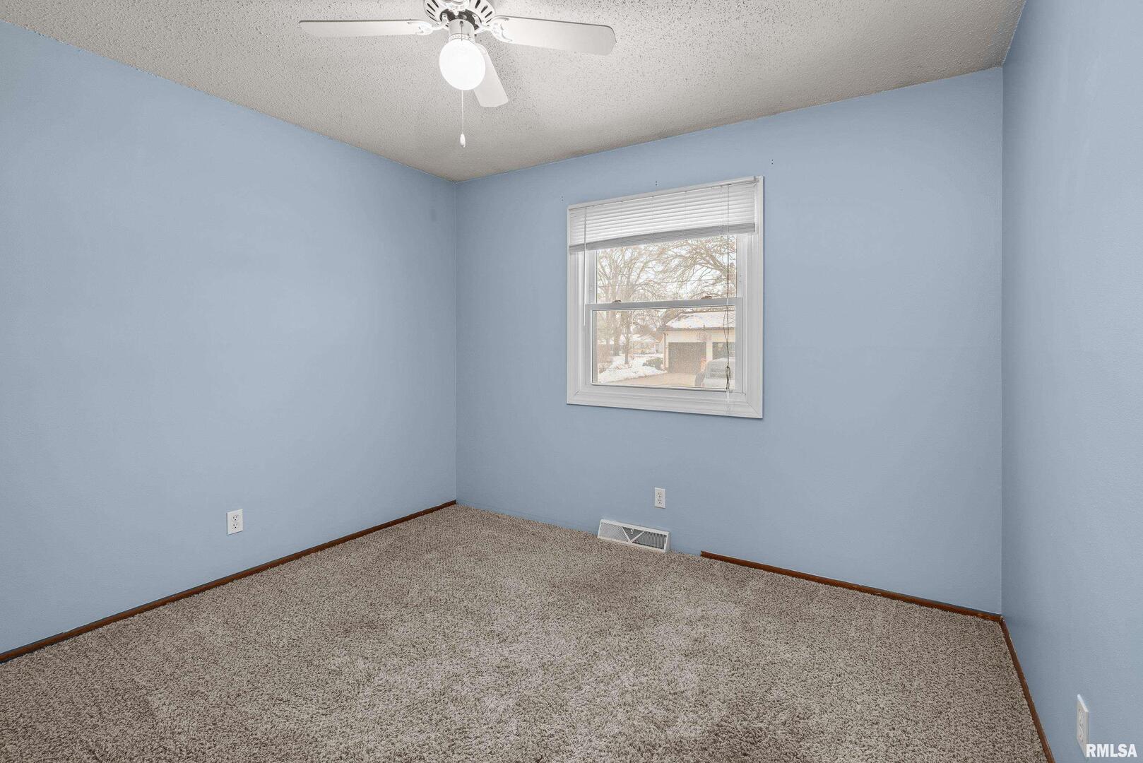 617 6th Street Camanche, IA 52730 - Photo 10 of 25 an empty room with a chandelier fan and windows