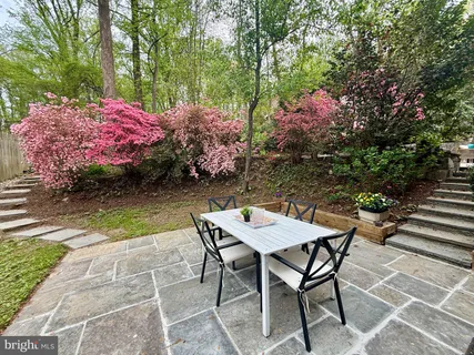 a patio with table and chairs and potted plants