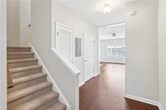 an empty room with wooden floor a ceiling fan a fireplace and windows