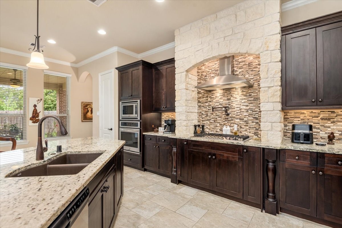 3771 Pinebrook Hollow Lane Spring, TX 77386 - Photo 10 of 50 This expert kitchen is super spacious allowing for great functionality while looking gorgeous with granite counters, full height tile backsplash, deep rich cabinetry stains, matt hardware pulls and under-cabinet lighting all comes together in elegance. The gas cooktop is complimented with an up top rare-to-find POT-FILLER