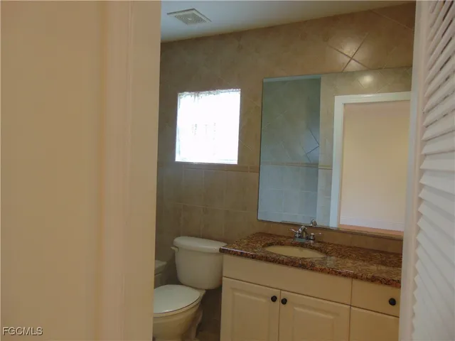 a bathroom with a granite countertop sink a toilet and a mirror