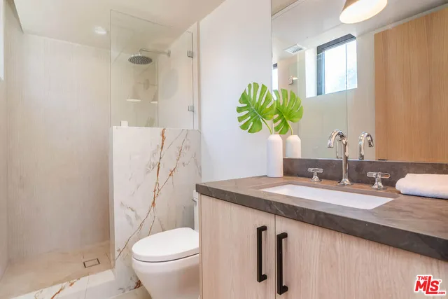 a bathroom with a granite countertop sink a toilet and a mirror