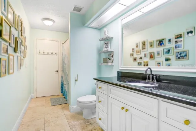 a bathroom with a granite countertop sink a toilet a mirror and shower