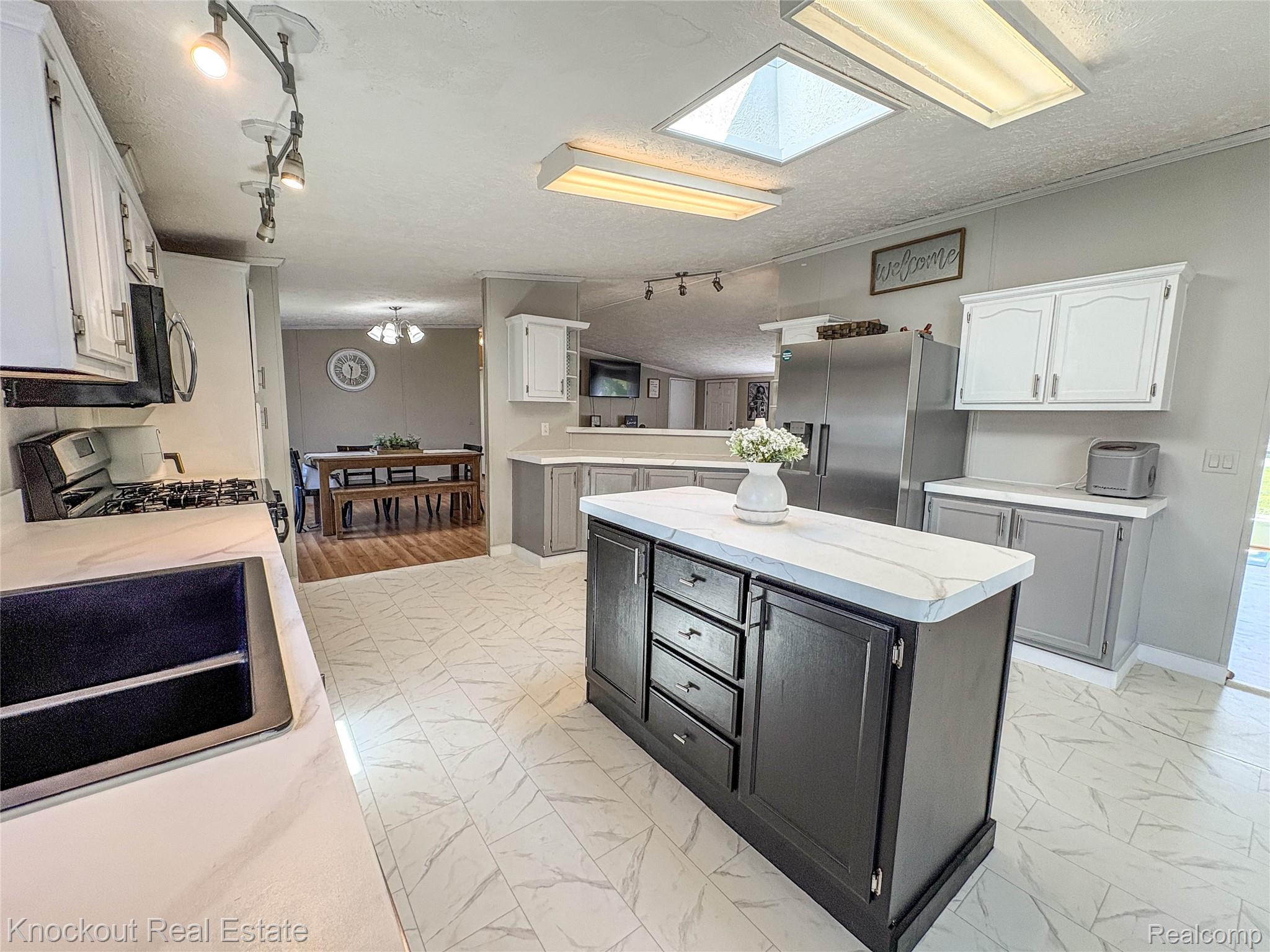 7760 Bell Road Birch Run, MI 48415 - Photo 18 of 68 Kitchen featuring a central island with storage, white countertops, stainless steel appliances, white upper cabinetry, and grey lower cabinetry