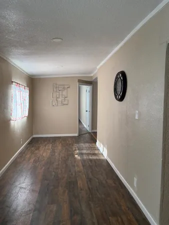 a view of an empty room with window and wooden floor