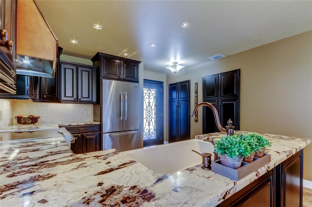 7003 Sunset Way, Unit 1 St. Pete Beach, FL 33706 - Photo 13 of 70 a kitchen with stainless steel appliances kitchen island granite countertop a refrigerator and a sink