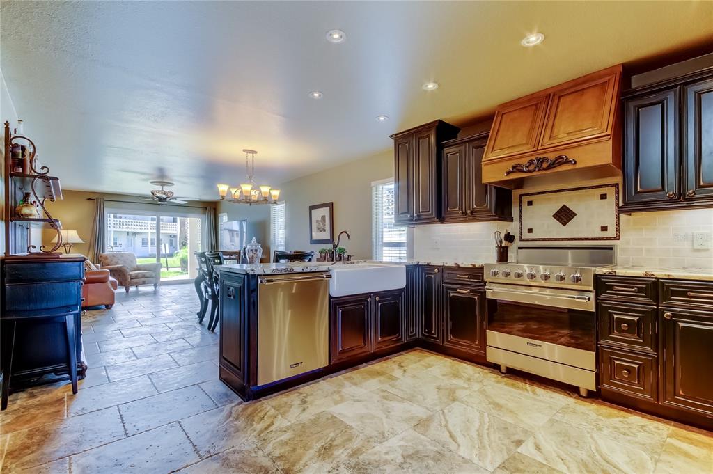 7003 Sunset Way, Unit 1 St. Pete Beach, FL 33706 - Photo 4 of 70 a kitchen with kitchen island granite countertop a stove top oven a sink a counter space and cabinets