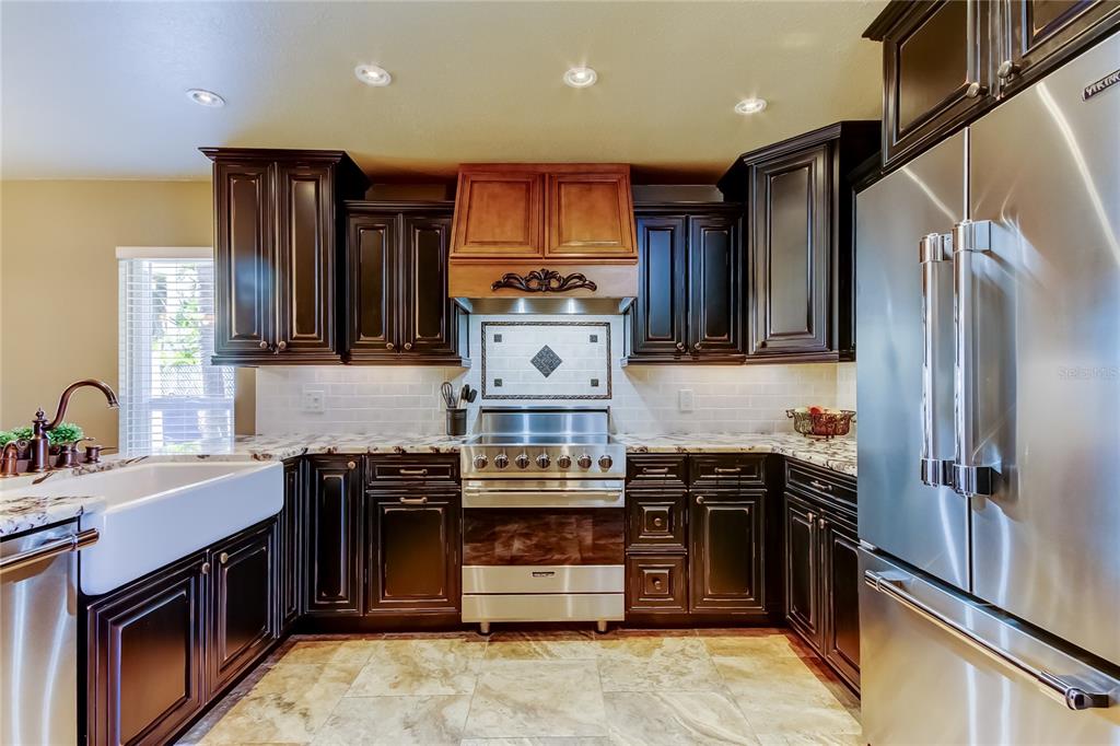 7003 Sunset Way, Unit 1 St. Pete Beach, FL 33706 - Photo 5 of 70 a kitchen with stainless steel appliances wooden cabinets and a stove top oven