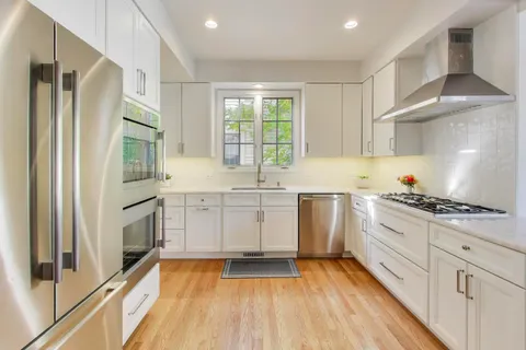a kitchen with stainless steel appliances granite countertop a refrigerator a stove and a wooden floors