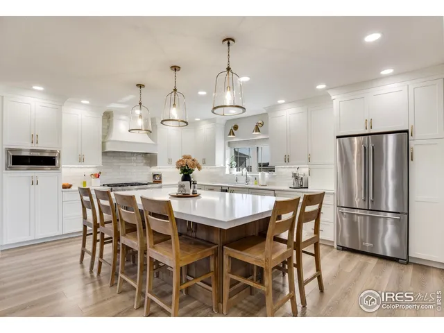 a kitchen with stainless steel appliances kitchen island granite countertop a dining table chairs and white cabinets