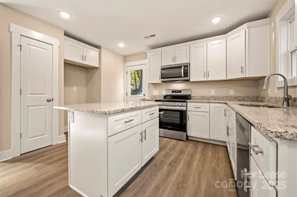 a kitchen with granite countertop white cabinets and white appliances