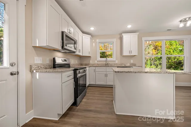 a kitchen with stainless steel appliances granite countertop a stove a sink and a microwave