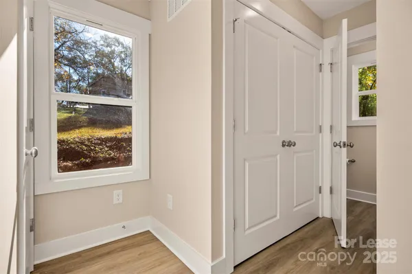a view of a hallway with wooden floor and closet