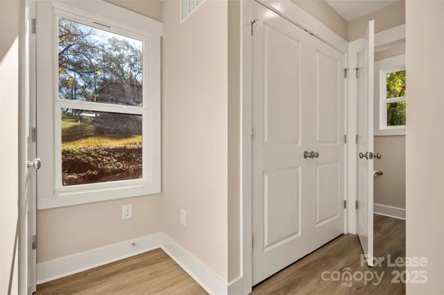 a view of a hallway with wooden floor and closet