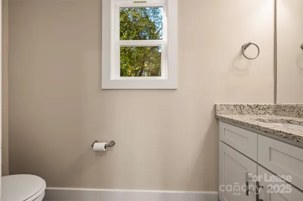a bathroom with a granite countertop sink and a toilet
