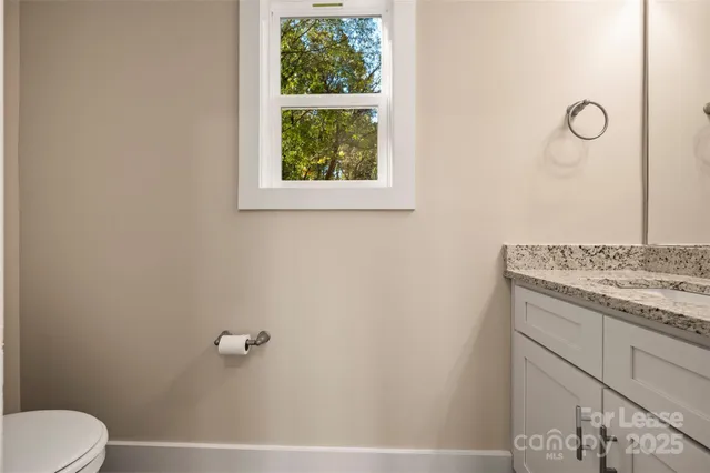 a bathroom with a granite countertop sink and a toilet