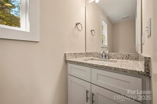 a bathroom with a granite countertop sink and a mirror