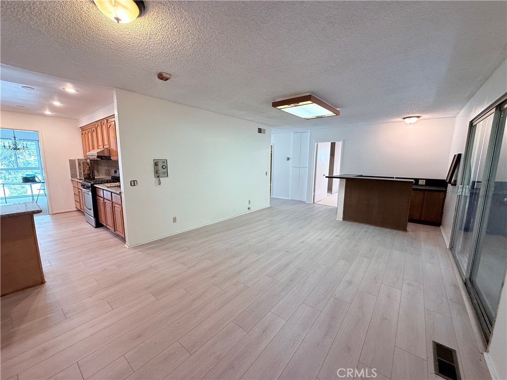 2575 Riverside Terrace Los Angeles, CA 90039 - Photo 11 of 29 an empty room with wooden floor and a kitchen view