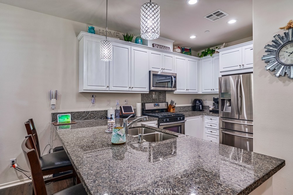 a kitchen with stainless steel appliances granite countertop a sink a stove a refrigerator cabinets and chairs