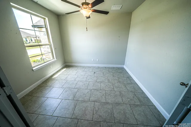 an empty room with windows and fan
