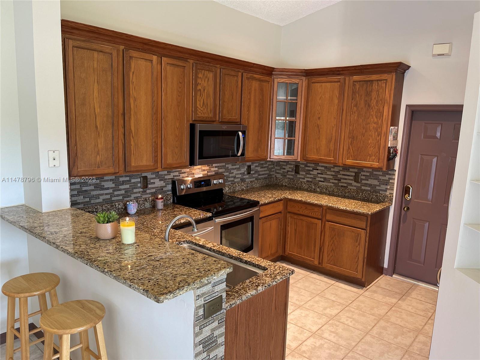 1135 Areca Way Weston, FL 33327 - Photo 14 of 45 a kitchen with granite countertop a sink stove and refrigerator