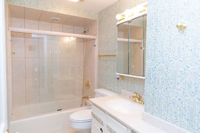 a bathroom with a granite countertop sink a toilet and shower