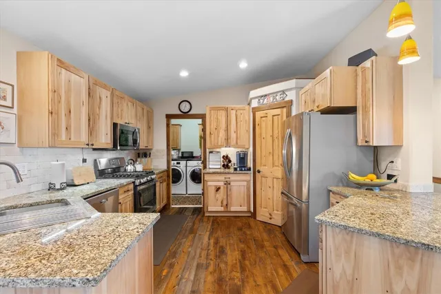 a kitchen with stainless steel appliances granite countertop a refrigerator stove sink and cabinets