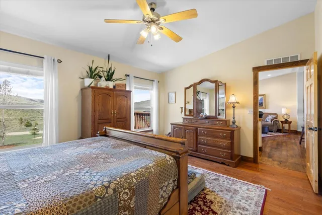 a spacious bedroom with a bed a dresser and wooden floor