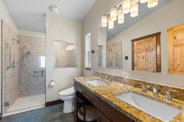 a bathroom with a granite countertop sink a toilet a mirror and shower
