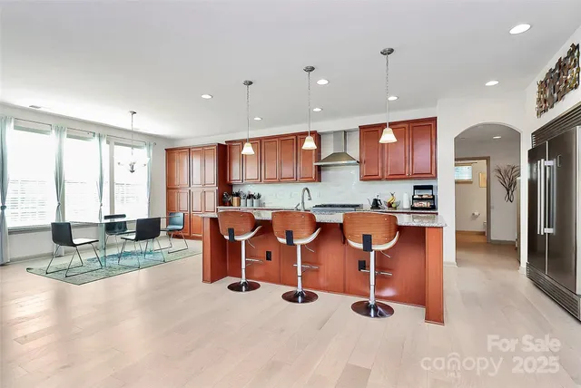 a view of kitchen with stainless steel appliances kitchen island granite countertop dining table chairs and a large window