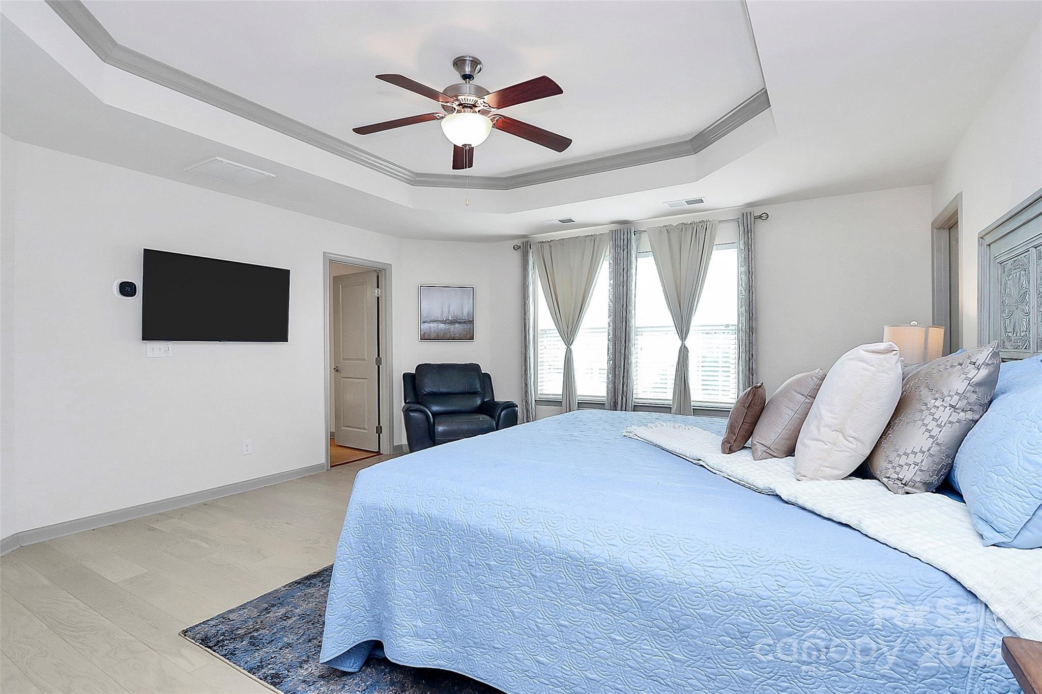 7362 Millstone Circle Southwest Concord, NC 28025 - Photo 30 of 45 a bedroom with a large bed a flat tv screen and a chandelier