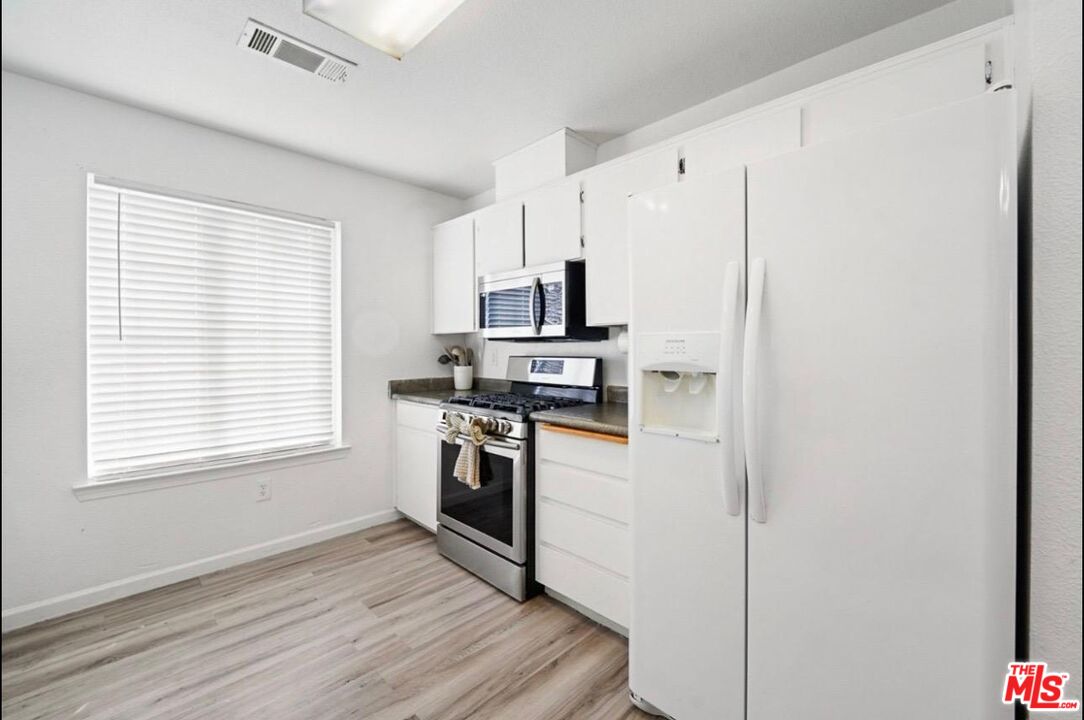 5612 McKee Road Bakersfield, CA 93313 - Photo 12 of 22 a kitchen with granite countertop white cabinets and stainless steel appliances