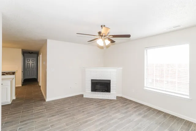 a view of an empty room with chandelier and fireplace