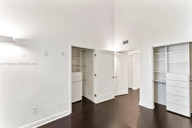 a view of a hallway with wooden floor and a bathroom