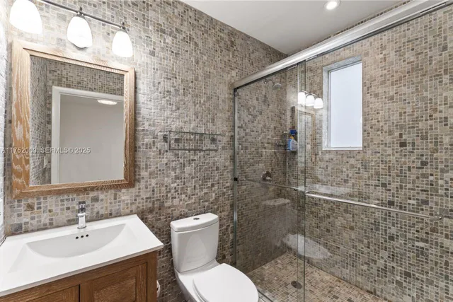 a view of a hallway with wooden floor and a bathroom