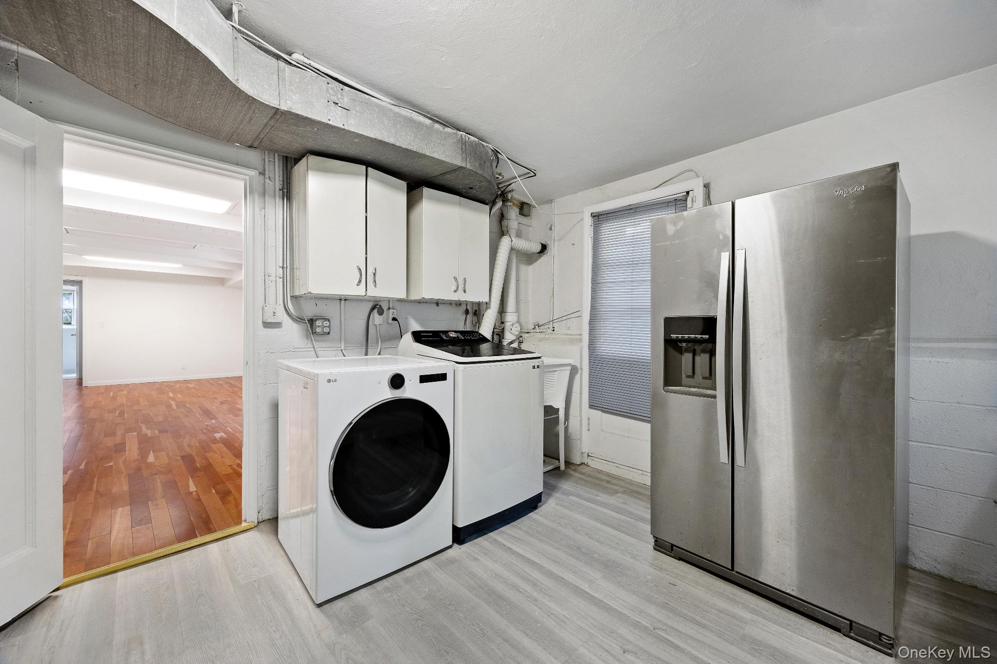 372 Heathcote Road Scarsdale, NY 10583 - Photo 18 of 20 Laundry area with light wood-style flooring, cabinet space, and washer and clothes dryer