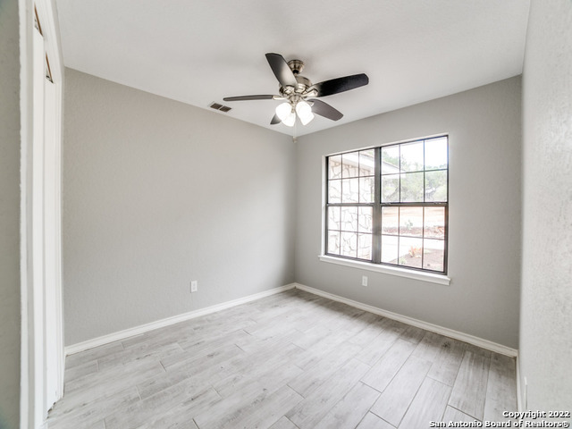 2580 Goat Hill Road Lakehills, TX 78063 - Photo 19 of 34 an empty room with wooden floor fan and windows