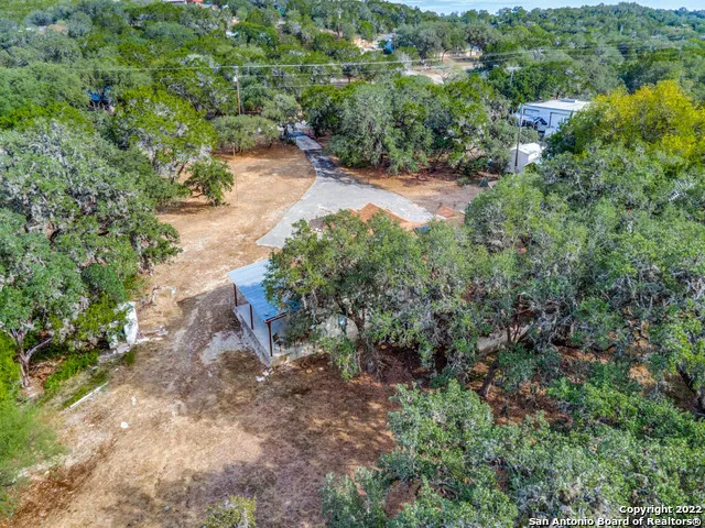 an aerial view of residential house with outdoor space and trees all around